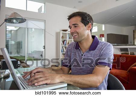 Stock Photography - Mixed race man using laptop. Fotosearch