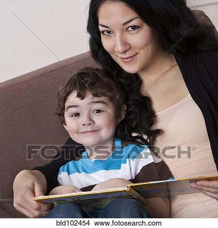 Picture - Mixed race mother reading book to son. Fotosearch