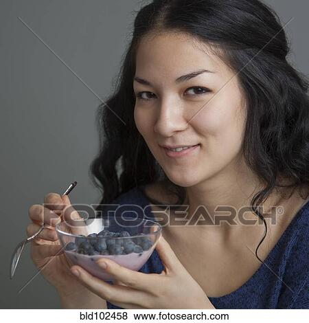 Stock Photo - Mixed race woman eating yogurt and fruit. Fotosearch