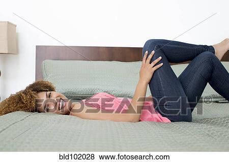 Stock Photo - Mixed race woman laying on bed. Fotosearch