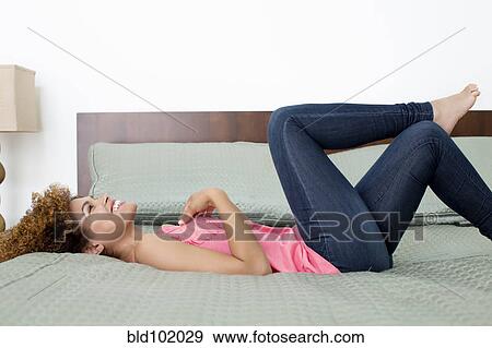 Stock Photo - Mixed race woman laying on bed. Fotosearch