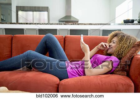 Mixed race woman laying on sofa using digital tablet View Large Photo Image Stock Photograph - Mixed race woman laying on sofa using digital tablet. Fotosearch