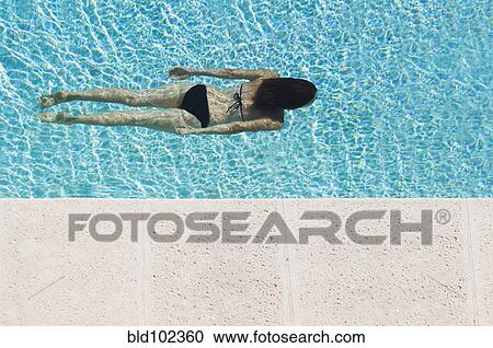 Stock Image - Mixed race woman swimming in pool. Fotosearch