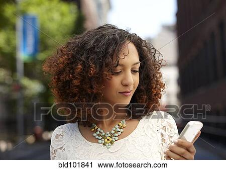 Stock Image - Mixed race woman using cell phone. Fotosearch