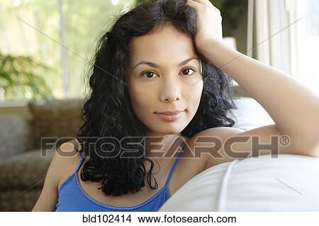Picture - Serious Hispanic woman sitting on sofa. Fotosearch