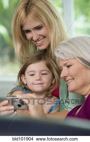 Smiling Caucasian grandmother, mother and daughter looking at digital camera View Large Photo Image Picture - Smiling Caucasian grandmother, mother and daughter looking at digital camera. Fotosearch