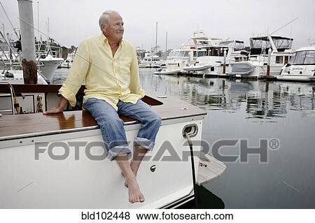 Smiling man sitting on boat in marina View Large Photo Image Stock Photo - Smiling man sitting on boat in marina. Fotosearch