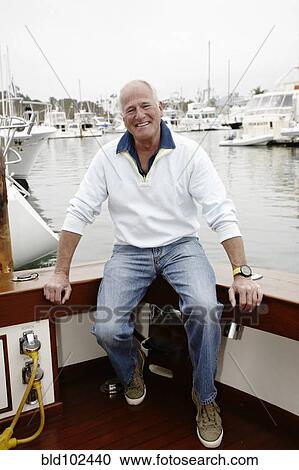 Stock Image - Smiling man sitting on boat. Fotosearch
