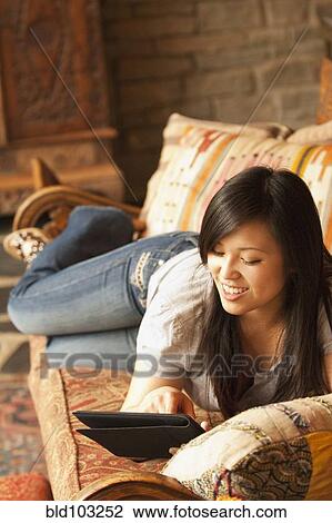 Asian woman using digital tablet on sofa View Large Photo Image Stock Image - Asian woman using digital tablet on sofa. Fotosearch