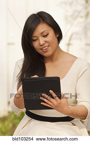 Picture - Asian woman using digital tablet. Fotosearch