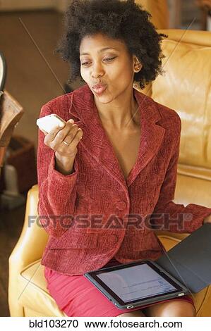 Stock Image - Black businesswoman with digital tablet talking on cell phone. Fotosearch