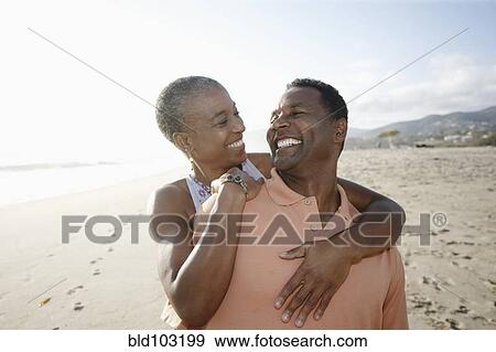 Stock Photo - Black couple hugging on beach. Fotosearch