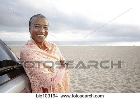 Picture - Black woman in shawl standing on beach. Fotosearch