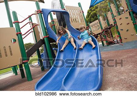 Brother and sister sliding down slide on playground View Large Photo Image Stock Photograph - Brother and sister sliding down slide on playground. Fotosearch