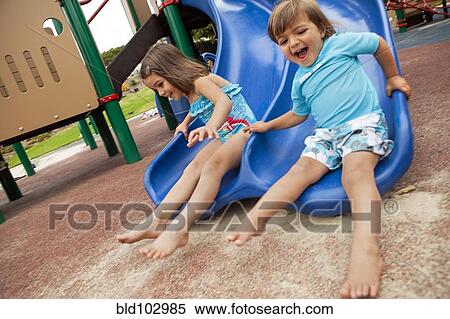 Brother and sister sliding down slide on playground View Large Photo Image Stock Photography - Brother and sister sliding down slide on playground. Fotosearch