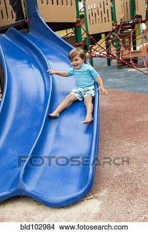 Carrera mezclada, niño, deslizar abajo resbaladero, en, patio de recreo