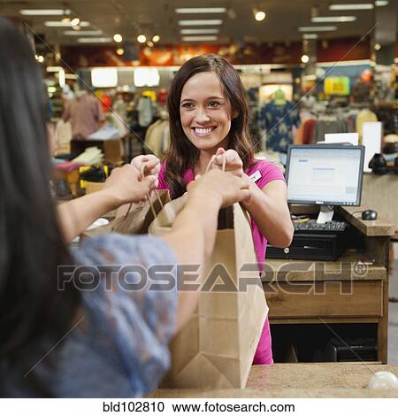 Cashier handing bags to woman in store View Large Photo Image Stock Image - Cashier handing bags to woman in store. Fotosearch