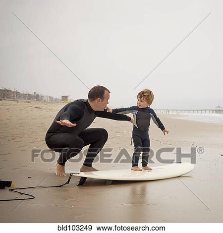 Stock Photo - Caucasian father teaching son to surf. Fotosearch