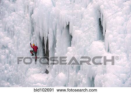 Stock Image - Caucasian man climbing ice wall. Fotosearch