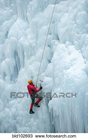 Stock Image - Caucasian man climbing ice wall. Fotosearch