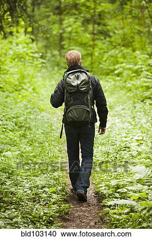 Stock Image - Caucasian man hiking in woods. Fotosearch