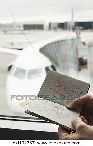 Caucasian man looking at passport in airport View Large Photo Image Stock Photo - Caucasian man looking at passport in airport. Fotosearch
