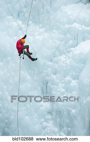 Stock Photo - Caucasian man rappelling down ice wall. Fotosearch