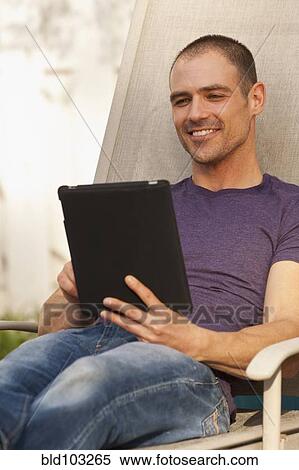 Caucasian man using digital tablet outdoors View Large Photo Image Stock Photography - Caucasian man using digital tablet outdoors. Fotosearch
