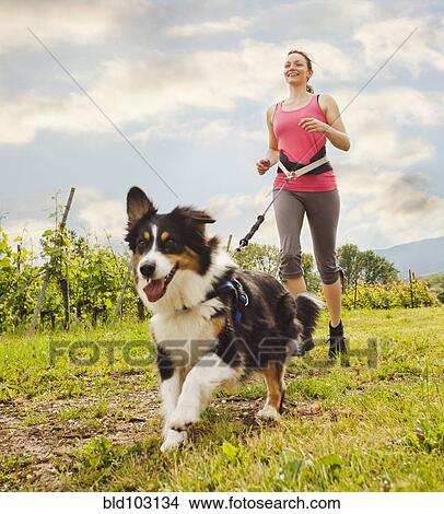 Picture - Caucasian woman running with dog. Fotosearch