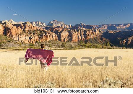Stock Image - Caucasian woman standing in remote field. Fotosearch
