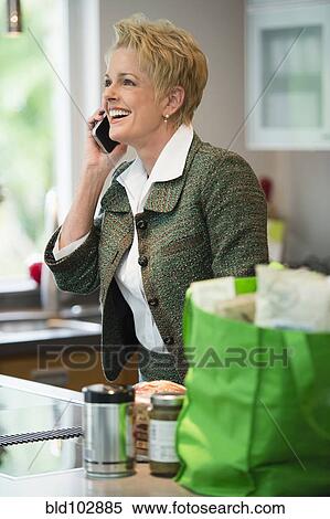 Caucasian woman using cell phone in kitchen View Large Photo Image Stock Photography - Caucasian woman using cell phone in kitchen. Fotosearch