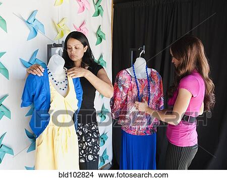 Picture - Co-workers dressing mannequins in store. Fotosearch