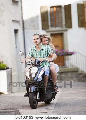 Stock Image - Couple riding scooter together. Fotosearch