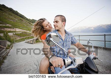 Couple riding scooter together View Large Photo Image Stock Image - Couple riding scooter together. Fotosearch