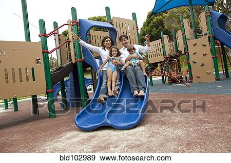 Stock Photo - Family sliding down slide on playground. Fotosearch