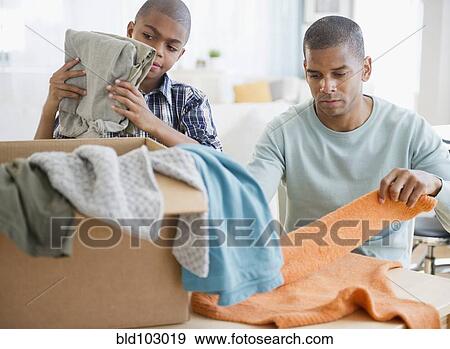 Father and son folding clothes for charity View Large Photo Image Stock Photo - Father and son folding clothes for charity. Fotosearch
