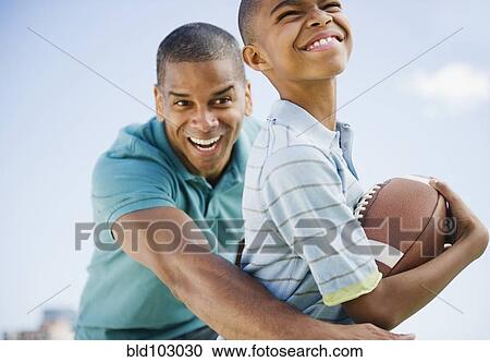Stock Image - Father and son playing football. Fotosearch