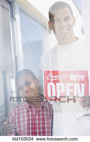 Father and son standing with open sign View Large Photo Image Picture - Father and son standing with open sign. Fotosearch