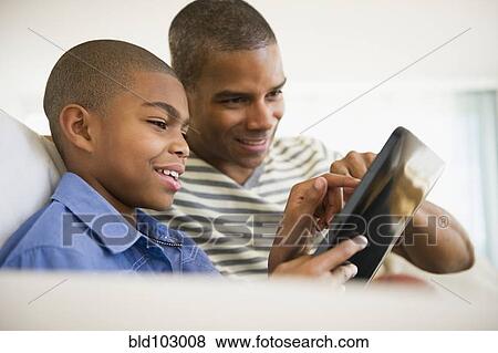 Father and son using digital tablet together View Large Photo Image Stock Photo - Father and son using digital tablet together. Fotosearch