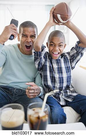Stock Photo - Father and son watching football on television. Fotosearch