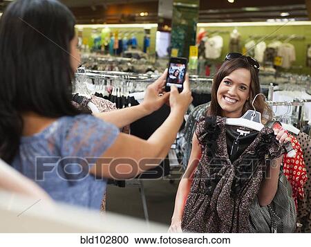 Friends shopping in clothing in store and taking pictures View Large Photo Image Stock Image - Friends shopping in clothing in store and taking pictures. Fotosearch