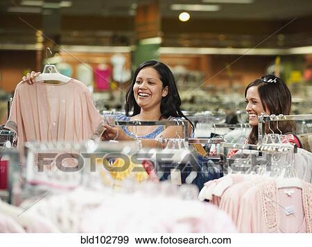 Stock Photo - Friends shopping in clothing in store. Fotosearch