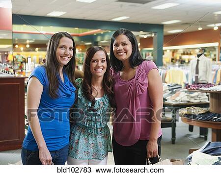 Stock Image - Friends shopping in clothing store. Fotosearch