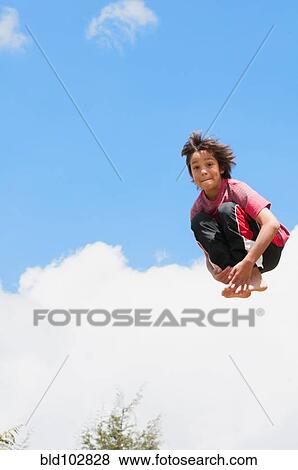 Stock Photo - Hispanic boy jumping in mid-air. Fotosearch