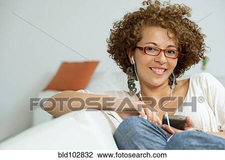 Stock Image - Hispanic woman listening to mp3 player. Fotosearch