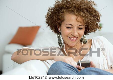 Stock Image - Hispanic woman listening to mp3 player. Fotosearch