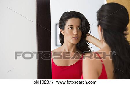 Hispanic woman looking at her reflection View Large Photo Image Stock Photo - Hispanic woman looking at her reflection. Fotosearch