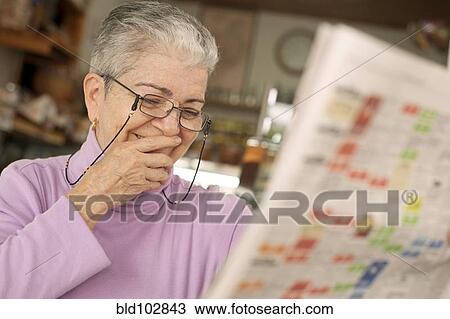 Stock Image - Hispanic woman reading newspaper. Fotosearch