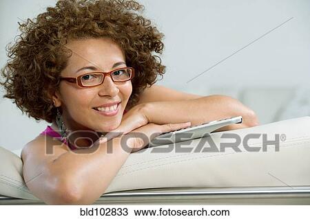 Hispanic woman sitting on sofa with remote control View Large Photo Image Stock Image - Hispanic woman sitting on sofa with remote control. Fotosearch