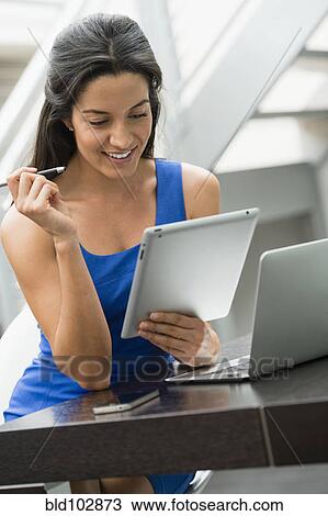 Stock Image - Hispanic woman using digital tablet. Fotosearch